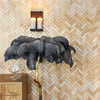Decorative feathered stand with gold base against a herringbone patterned wall.