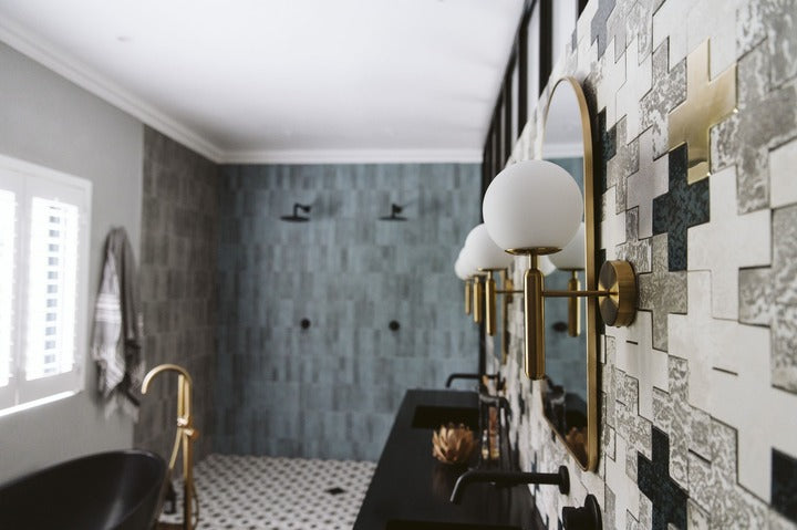 Modern bathroom with tiled walls, a sink, and decorative lighting fixtures.