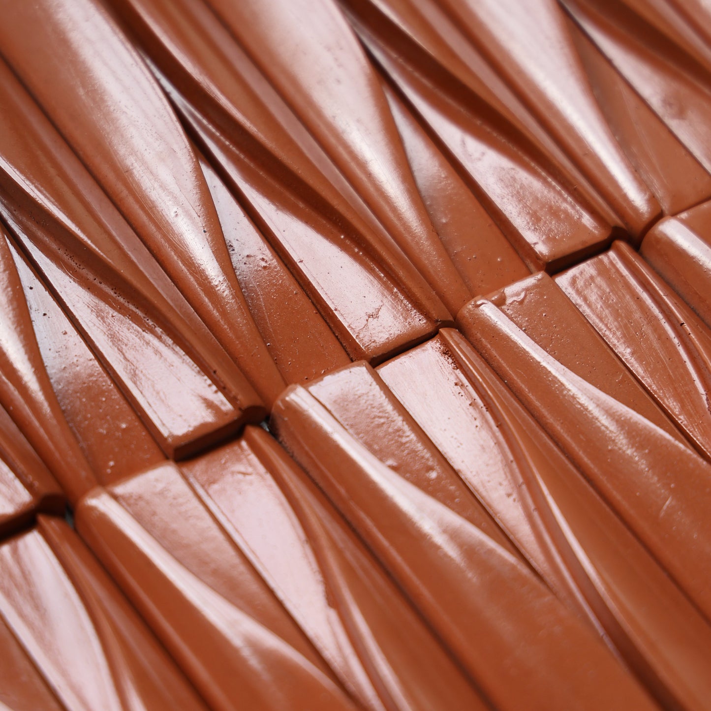 
                  
                    Close-up of a glossy brown textured surface with repeating diagonal ridges and a warm coppery-orange sheen.
                  
                