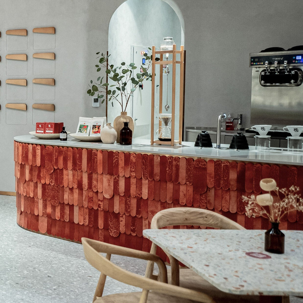 Modern interior with a red textured wall, wooden chairs, and a dining table.